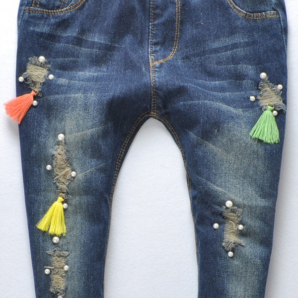 Blugi de copii pentru o fata cu ciucuri colorati si motive rupte