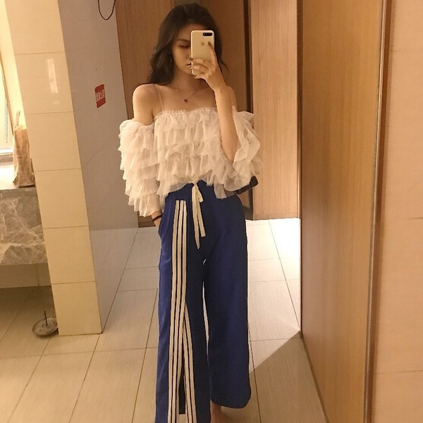 Σύντομο γυναικείο μπλουζάκι  με ανοιχτούς ώμους και ανοιχτού χρώματος βολάν