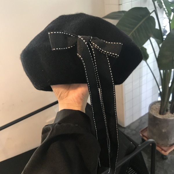 Pălărie modernă de iarnă pentru femei cu o panglică în negru