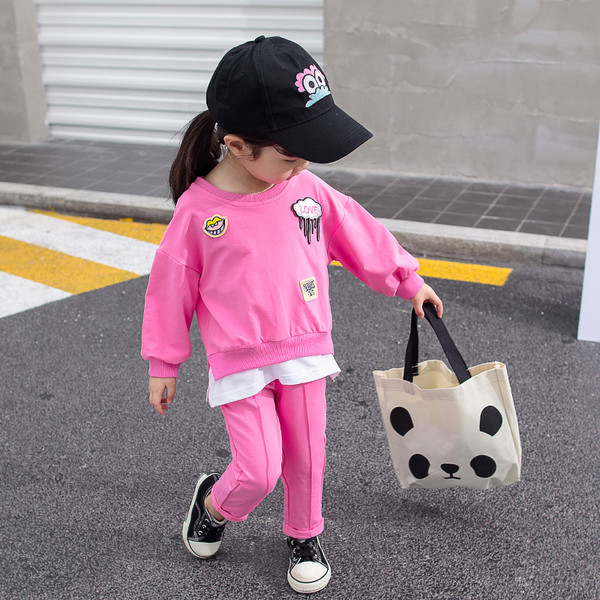 Gyerekkészlet lányoknak rózsaszínben két részből áll - emblémákkal ellátott blúz és nadrág