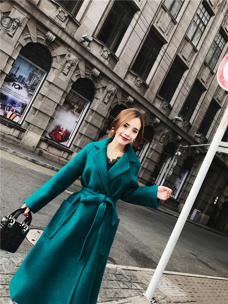 Elegáns női kabát nagy zsebekkel és kék övvel