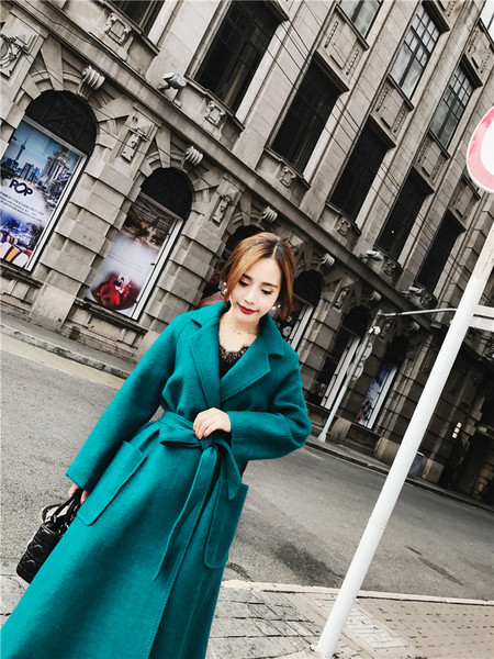 Elegáns női kabát nagy zsebekkel és kék övvel