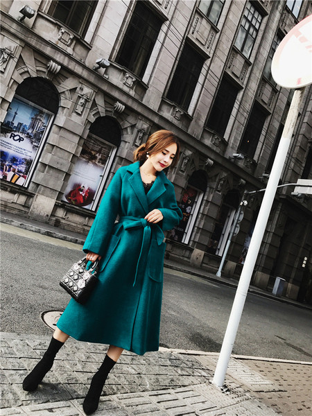 Elegáns női kabát nagy zsebekkel és kék övvel