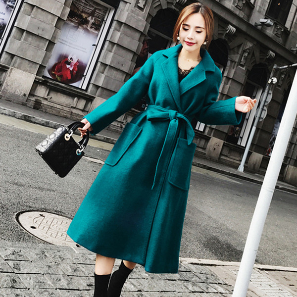 Elegáns női kabát nagy zsebekkel és kék övvel