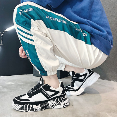 Modern férfi tornacipő magas talppal, fehér és fekete színben, feliratokkal