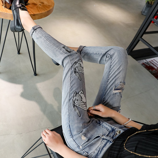 Modern női farmer szakadt motívummal és emblémával