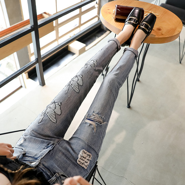 Modern női farmer szakadt motívummal és emblémával