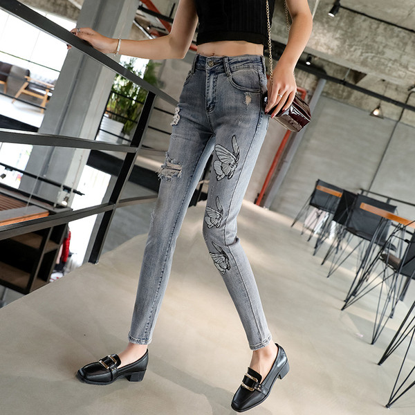 Modern női farmer szakadt motívummal és emblémával