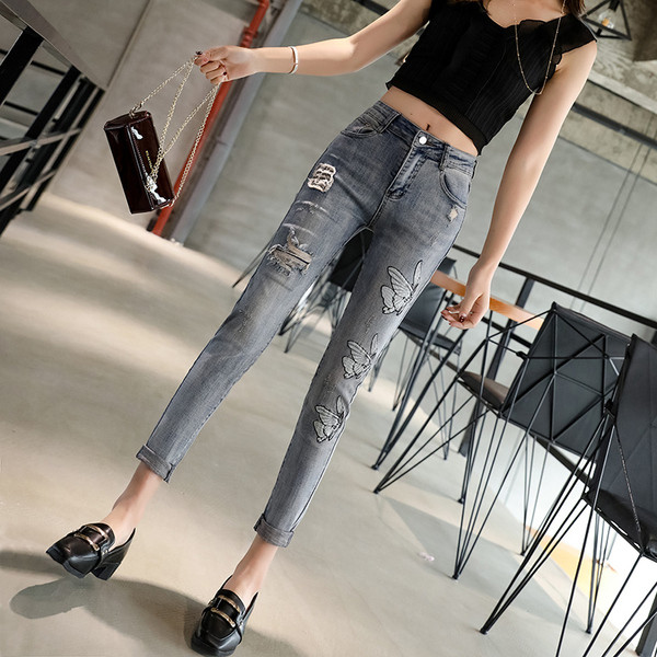 Modern női farmer szakadt motívummal és emblémával