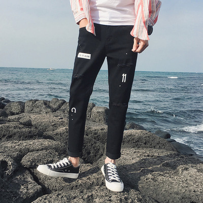 Modern férfi farmer fekete színben, szakadt motívumokkal és applikációkkal