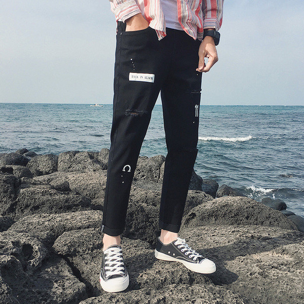 Modern férfi farmer fekete színben, szakadt motívumokkal és applikációkkal