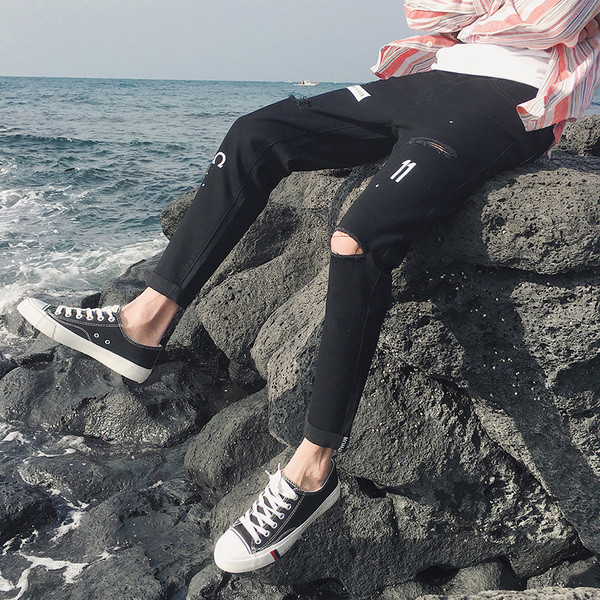 Modern férfi farmer fekete színben, szakadt motívumokkal és applikációkkal