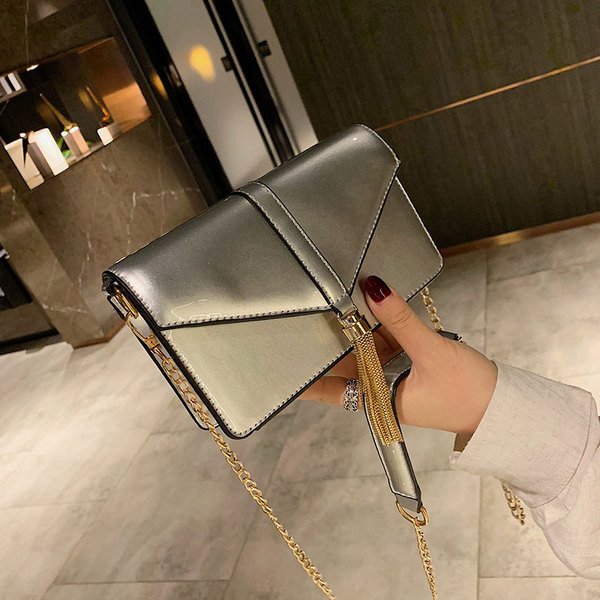 Κομψή γυναικεία τσάντα σε τέσσερα χρώματα με μακρά μεταλλική λαβή και τρισδιάστατα μεταλλικά στοιχεία