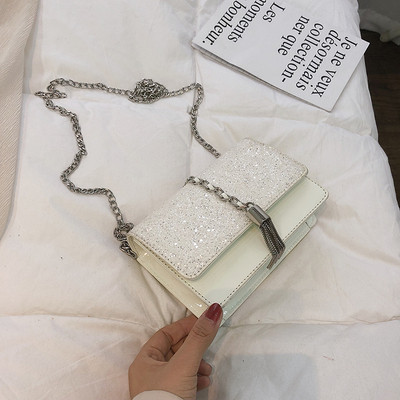 Stílusos kézitáska három színben fényes elemekkel és fémlánccal