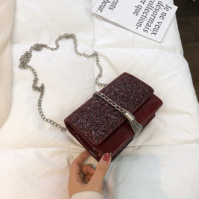 Stílusos kézitáska három színben fényes elemekkel és fémlánccal