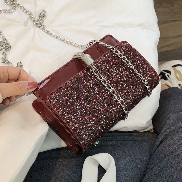 Stílusos kézitáska három színben fényes elemekkel és fémlánccal