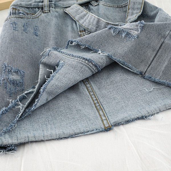 Modern női farmerszoknya szakadt elemekkel