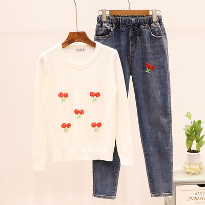 Modern női szett, amely egy fehér pulóvert és egy farmert tartalmaz hímzéssel