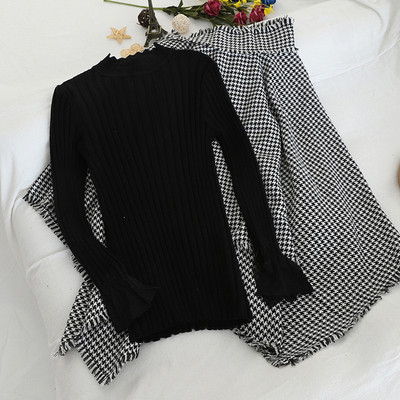 Set de damă care include un pulover negru și o fustă în carouri cu talie înaltă