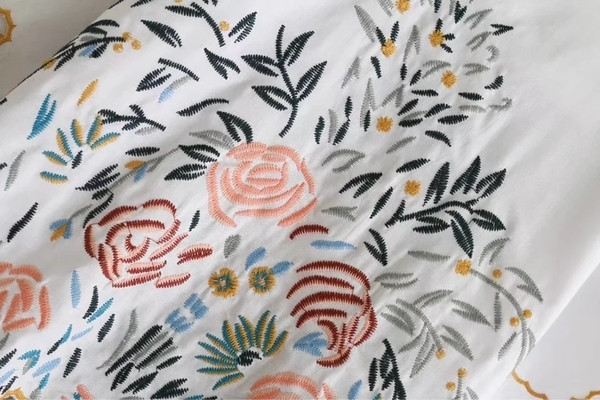 Alkalmi női póló virágos motívummal, kivágott ujjakkal, fehér színben