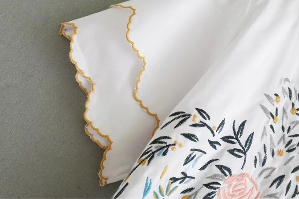 Alkalmi női póló virágos motívummal, kivágott ujjakkal, fehér színben