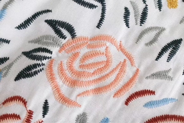 Alkalmi női póló virágos motívummal, kivágott ujjakkal, fehér színben