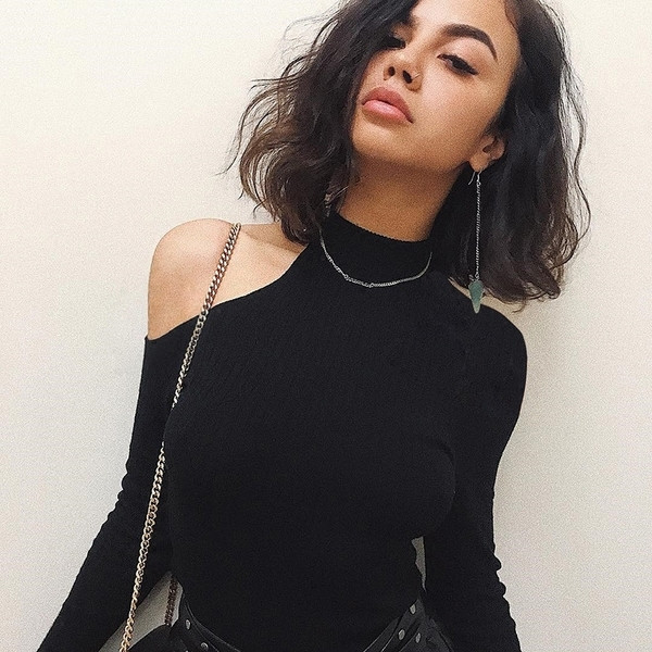 Κομψή γυναικεία μπλούζα σε ένα απλό μοντέλο με γυμνό ώμο σε μαύρο χρώμα