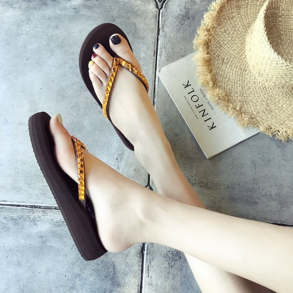 Papuci de dama peste varf pe o platforma cu pietre