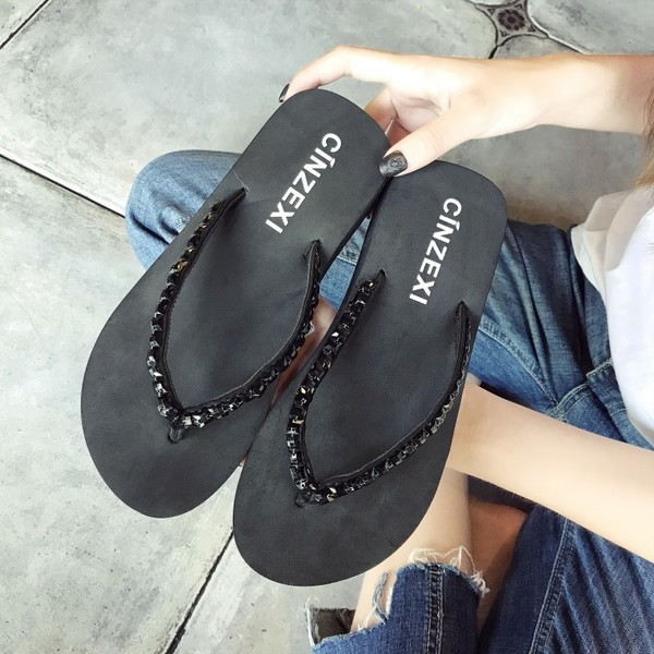 Papuci de dama peste varf pe o platforma cu pietre