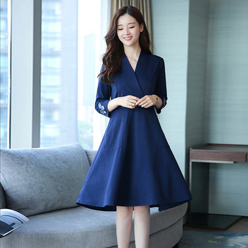 Az elegáns női ruha mély V-nyakkal, gyönyörű hímzéssel és zsebekkel