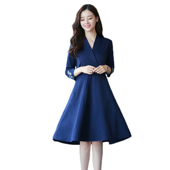 Az elegáns női ruha mély V-nyakkal, gyönyörű hímzéssel és zsebekkel