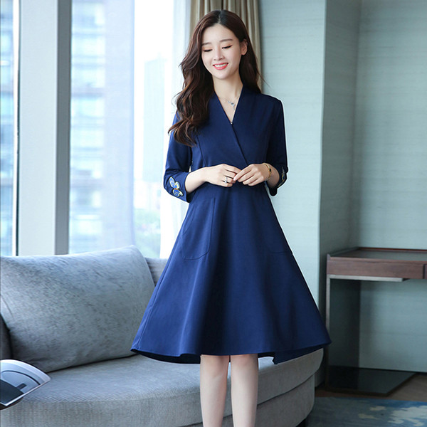 Az elegáns női ruha mély V-nyakkal, gyönyörű hímzéssel és zsebekkel