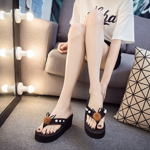 Női papucs a lábujj felett egy bolyhos és díszkövekkel díszített emelvényen