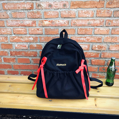 Női mindennapi hátizsák érdekes első zsebbel és szalagdísszel