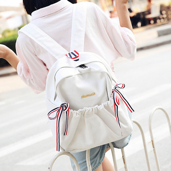 Női mindennapi hátizsák érdekes első zsebbel és szalagdísszel