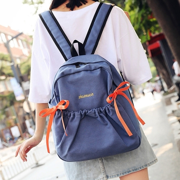 Női mindennapi hátizsák érdekes első zsebbel és szalagdísszel