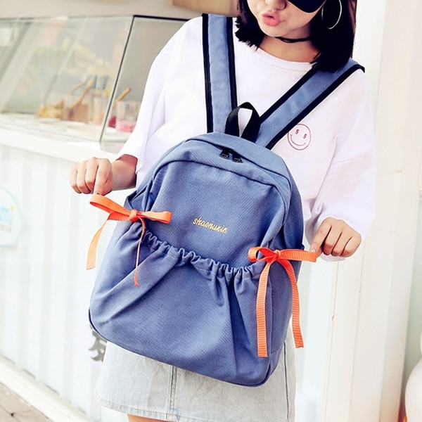 Női mindennapi hátizsák érdekes első zsebbel és szalagdísszel