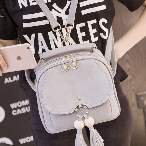 Elegáns női hátizsák két színben fém elemekkel és bojttal