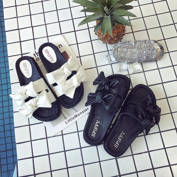 Praktikus női papucs puha talppal, fehér és fekete színben, szalagokkal díszítve