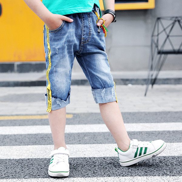 Blugi moderni pentru copii cu elemente metalice și dungi laterale colorate cu o inscripție