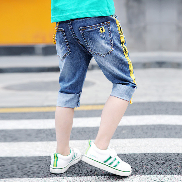 Blugi moderni pentru copii cu elemente metalice și dungi laterale colorate cu o inscripție