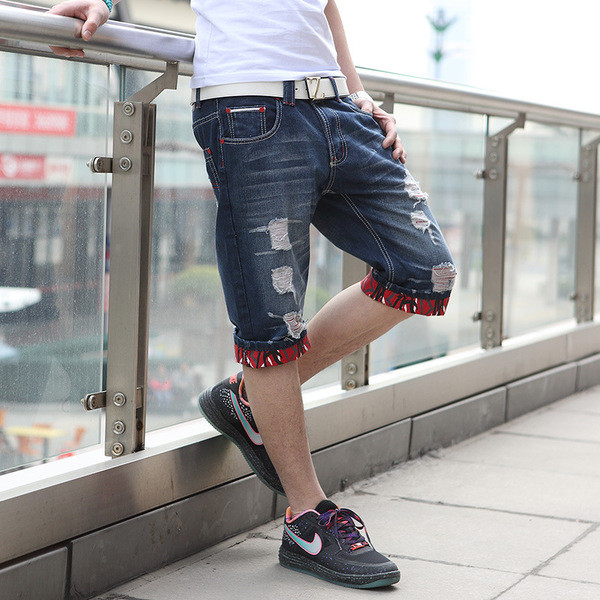 Sötét színű, szakadt motívumokkal ellátott rövid férfi farmer